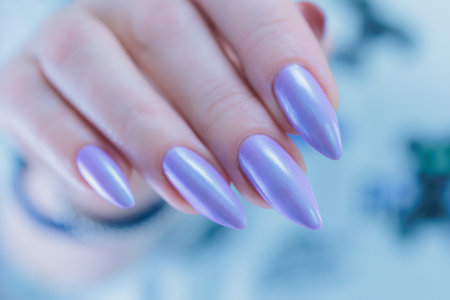 Female hand with long nails and a lilac blue nail polishの写真素材