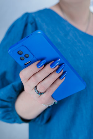 Woman's hands holding a large blue smartphoneの写真素材