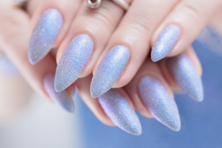 Woman's beautiful hand with long nails and light baby blue manicureの写真素材