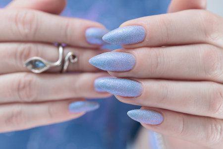 Woman's beautiful hand with long nails and light baby blue manicureの写真素材