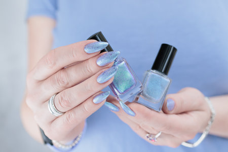 Woman's beautiful hand with long nails and light blue and lilac manicure