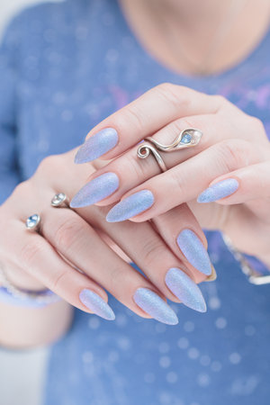 Woman's beautiful hand with long nails and light baby blue manicureの写真素材