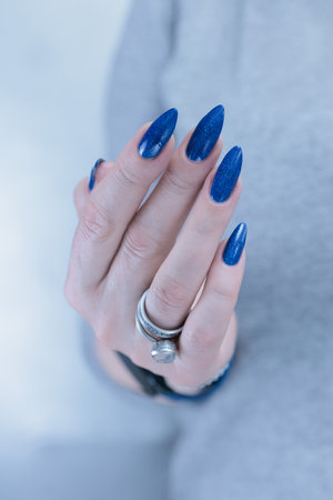 Woman's beautiful hand with long nails and dark blue manicureの写真素材