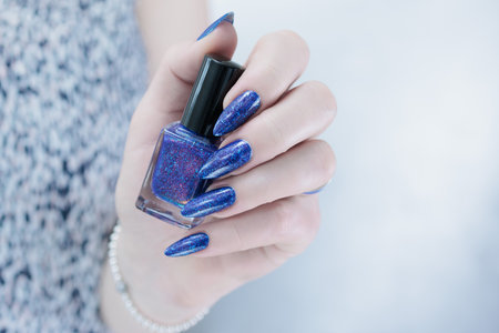 Woman's beautiful hand with long nails and dark blue manicureの写真素材