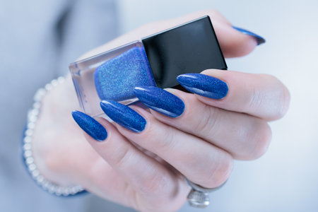 Woman's beautiful hand with long nails and dark blue manicureの写真素材