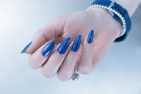Woman's beautiful hand with long nails and dark blue manicureの写真素材