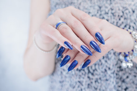 Woman's beautiful hand with long nails and dark blue manicureの写真素材
