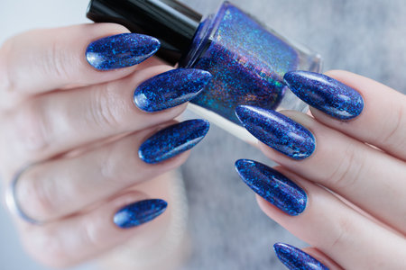 Woman's beautiful hand with long nails and dark blue manicureの写真素材