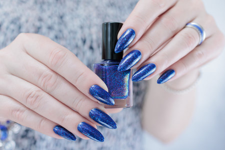Woman's beautiful hand with long nails and bright blue purple manicure