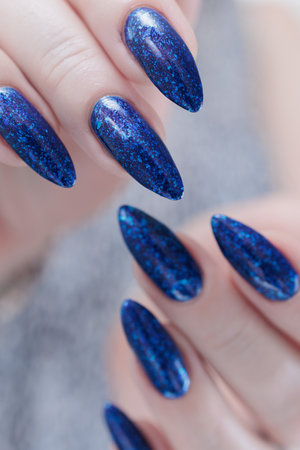 Woman's beautiful hand with long nails and dark blue manicureの写真素材