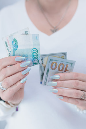 female hands holding Russian rubles and American dollar paper billsの写真素材