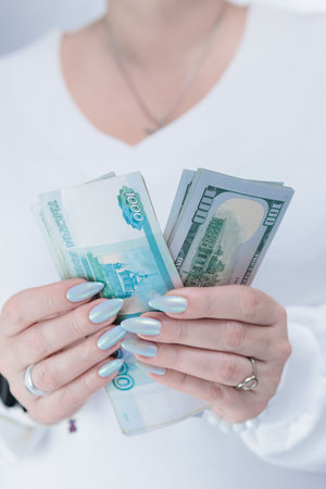 female hands holding Russian rubles and American dollar paper billsの写真素材