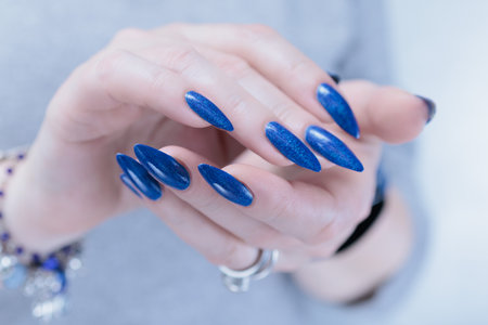 Woman's beautiful hand with long nails and bright blue purple manicureの写真素材