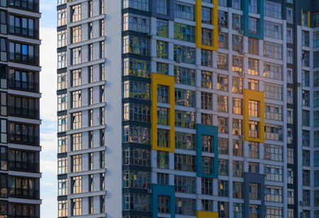 Modern buildings, walls and windows, reflections and sun rays. City view on a sunny day.
