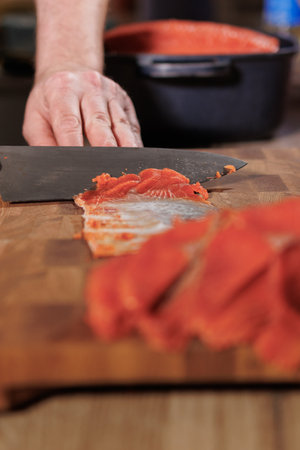 Male hands cutting red salmon fish on a wooden board