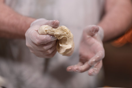Hands in gloves kneading dough for bakingの写真素材