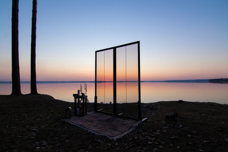 Decorative elements for festive events, photo zone with flowers and candles, glass window or doors. Orange and blue sky at sunset in the evening and night.の写真素材
