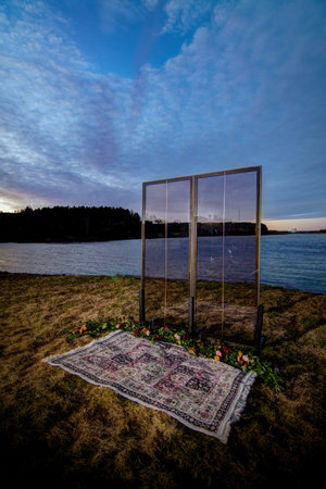 Decorative elements for festive events, photo zone with flowers and candles, glass window or doors. Orange and blue sky at sunset in the evening and night.の写真素材