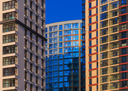 Modern buildings, walls and windows, reflections and sun rays. City view on a sunny day.