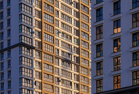 Modern buildings, walls and windows, reflections and sun rays. City view on a sunny day.