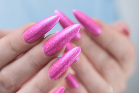 beautiful female hands with long nails and bright neon pink red nail polishの写真素材