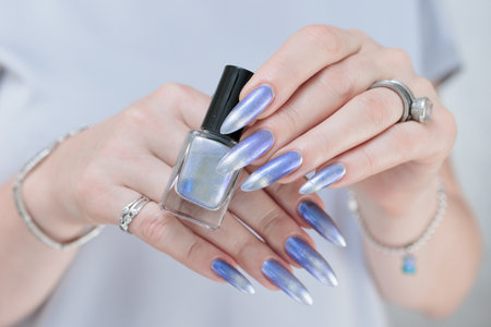 Female hand with long nails and bright light blue and silver manicureの写真素材