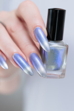 Female hand with long nails and bright light blue and silver manicureの写真素材