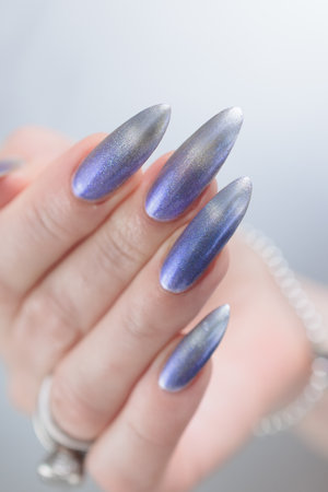 Female hand with long nails and bright light blue and silver manicureの写真素材