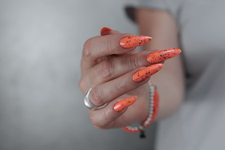 Hand with long nails and light orange neon manicureの写真素材
