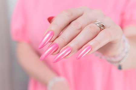 beautiful female hands with long nails and bright neon pink red nail polishの写真素材