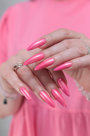 beautiful female hands with long nails and bright neon pink red nail polishの写真素材