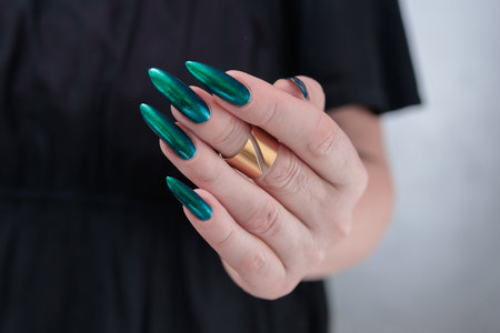 Woman's hand with long nails and green blue nail polishの写真素材