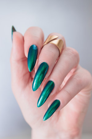 Woman's beautiful hand with long nails and blue and green nail polishの写真素材