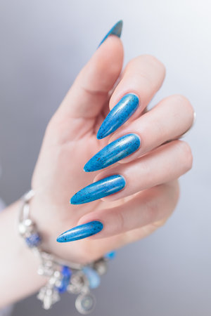 Woman's beautiful hand with long nails and bright blue manicureの写真素材
