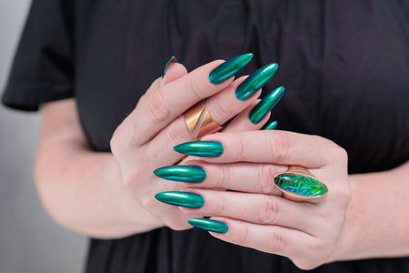 Woman's hand with long nails and green blue nail polishの写真素材
