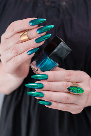Woman's hand with long nails and black green nail polish