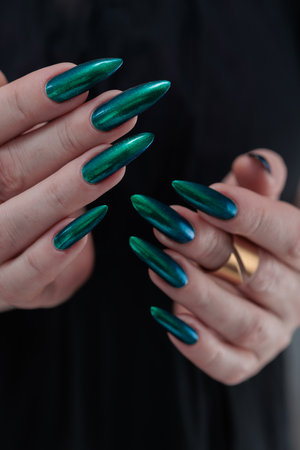 Woman's hand with long nails and green nail polishの写真素材