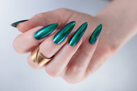 Woman's hand with long nails and green blue nail polishの写真素材
