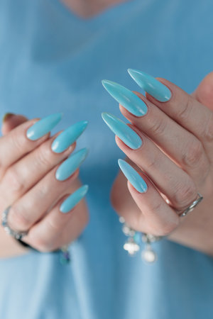 Woman's beautiful hand with long nails and baby blue manicureの写真素材