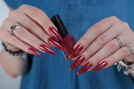 Female hands with long nails and red nail polishの写真素材