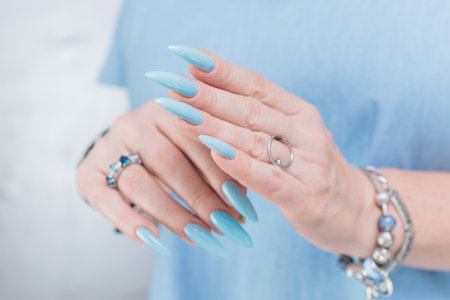 Female hand with long nails and bright light blue and silver manicureの写真素材