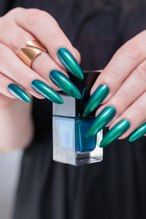 Woman's hand with long nails and green blue nail polishの写真素材