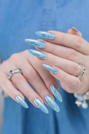Female hand with long nails and bright light blue and silver manicureの写真素材