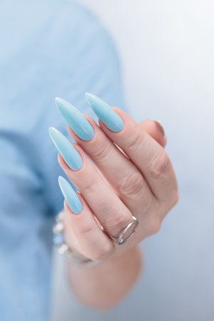 Woman's beautiful hand with long nails and light baby blue manicureの写真素材