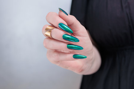 Woman's beautiful hand with long nails and blue and green nail polishの写真素材