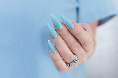Woman's beautiful hand with long nails and baby blue manicureの写真素材