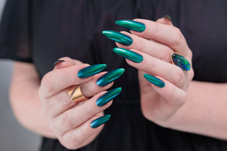 Woman's beautiful hand with long nails and blue and green nail polishの写真素材