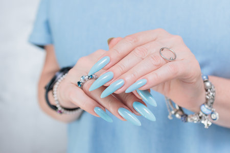 Woman's beautiful hand with long nails and light baby blue manicureの写真素材