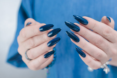 Woman's beautiful hand with long nails and dark blue manicureの写真素材