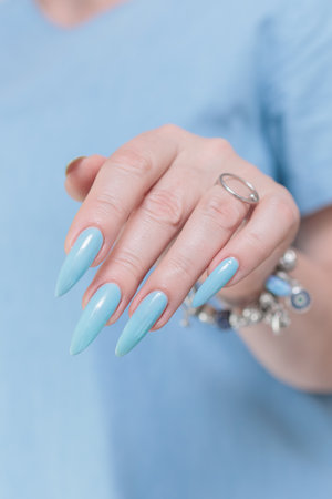 Woman's beautiful hand with long nails and baby blue manicureの写真素材